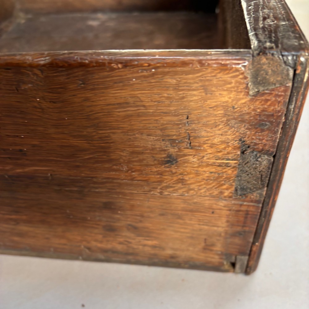 A late 17th-century dark oak low dresser featuring geometric moulded drawer fronts, brass teardrop handles, and turned front legs. View IX
