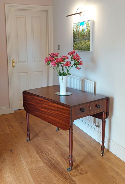 fig 1. A Regency mahogany Pembroke table featuring drop flaps, a drawer with turned wood knobs, and reeded turned legs on brass castors.