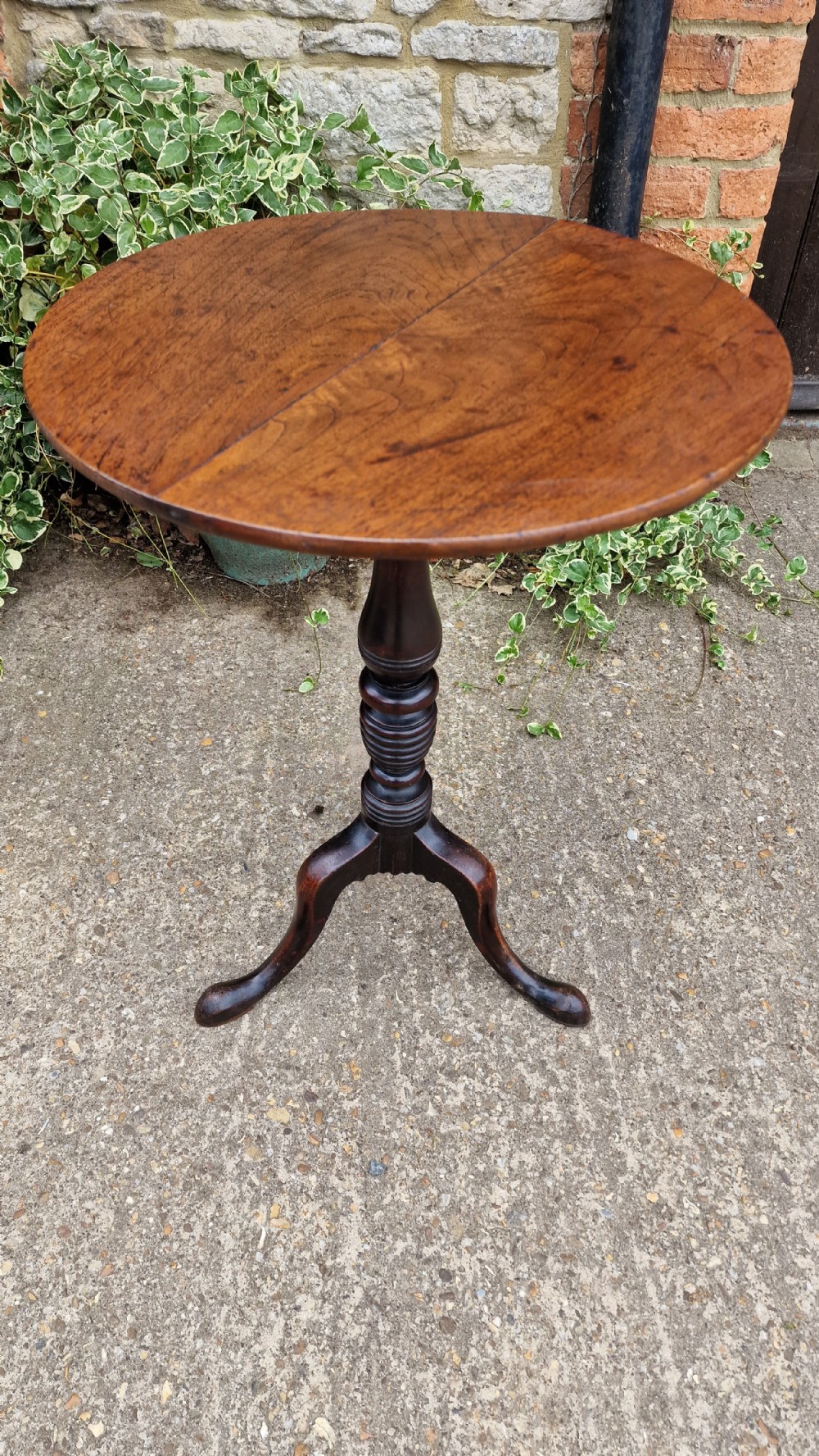 A Georgian fruitwood tilt top wine table with a circular top, turned central column, and tripod cabriole legs on pad feet.