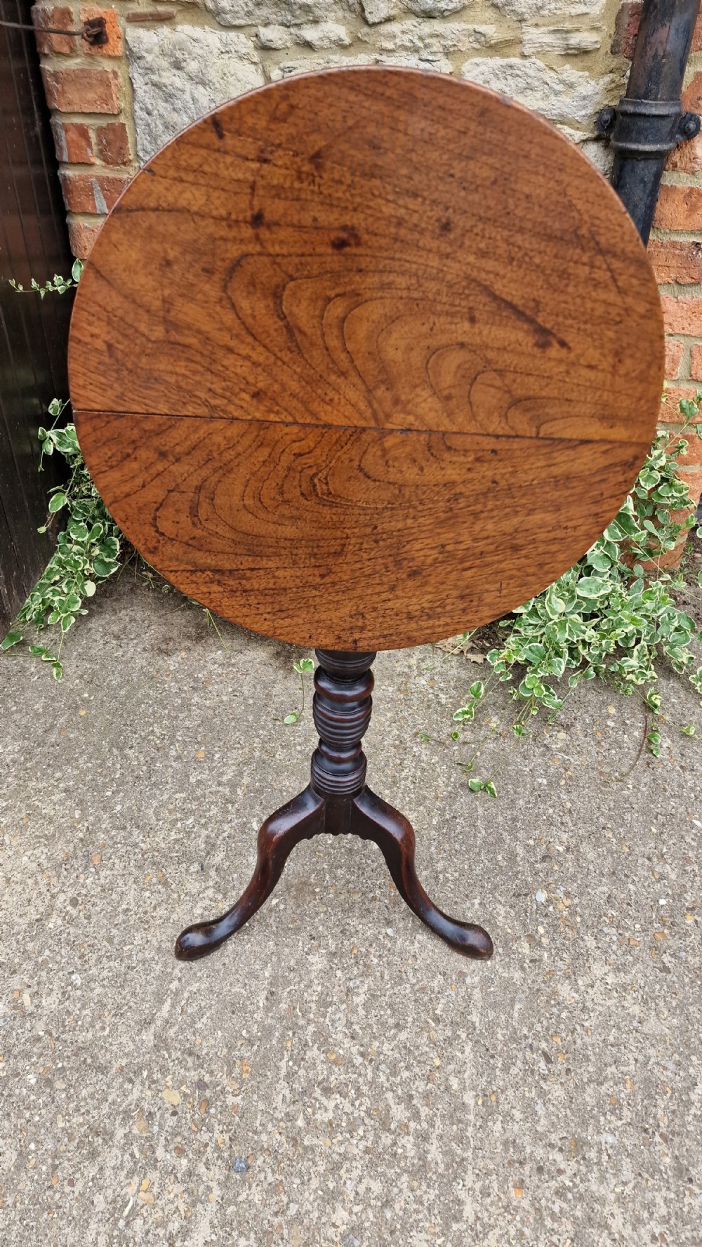 A Georgian fruitwood tilt top wine table with a circular top, turned central column, and tripod cabriole legs on pad feet. View VII