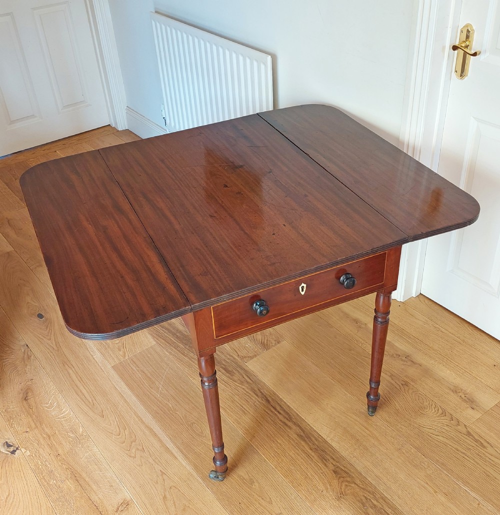 A Regency mahogany Pembroke table featuring drop flaps, a drawer with turned wood knobs, and reeded turned legs on brass castors. View XI