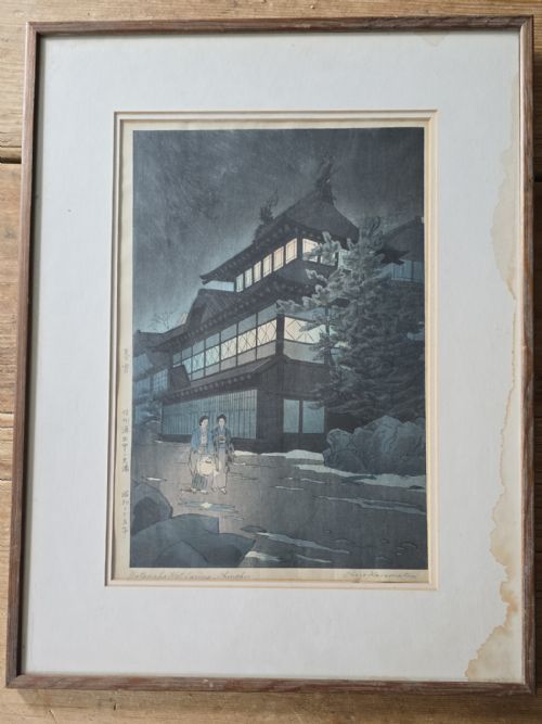 fig 1. A mid-century Japanese woodblock print portraying a dark nocturnal scene of a traditional hot spring inn with glowing windows and two figures carrying a lantern.