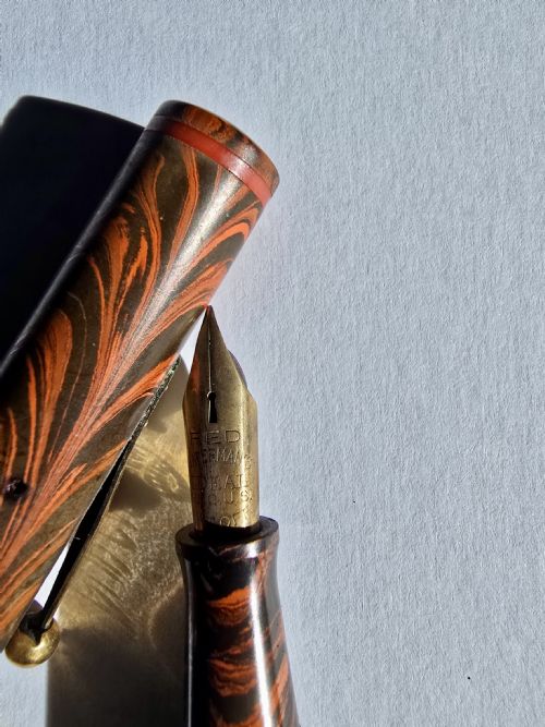 fig 1. A vintage Waterman Ideal No. 7 lever-fill fountain pen crafted from red and black rippled ebonite with gold-toned trim.