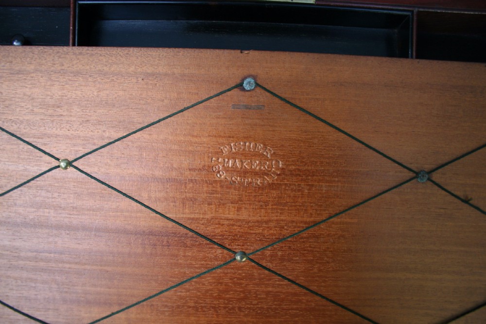 A rectangular early Victorian mahogany writing box featuring flush brass binding, brass corner plates, a central brass plaque, and a brass keyhole with a key inserted. View III