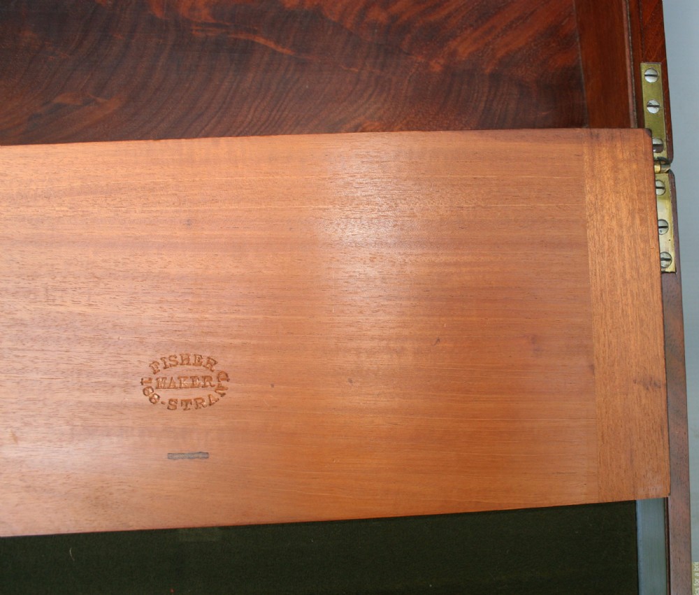 A rectangular early Victorian mahogany writing box featuring flush brass binding, brass corner plates, a central brass plaque, and a brass keyhole with a key inserted. View IV
