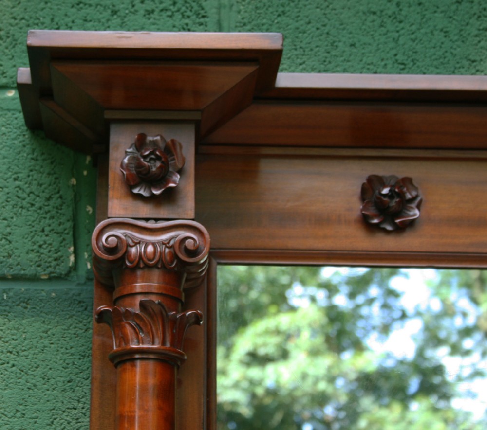 An early Victorian flame mahogany overmantel mirror featuring side columns with carved Corinthian capitals and a frieze decorated with carved rosettes. View IV