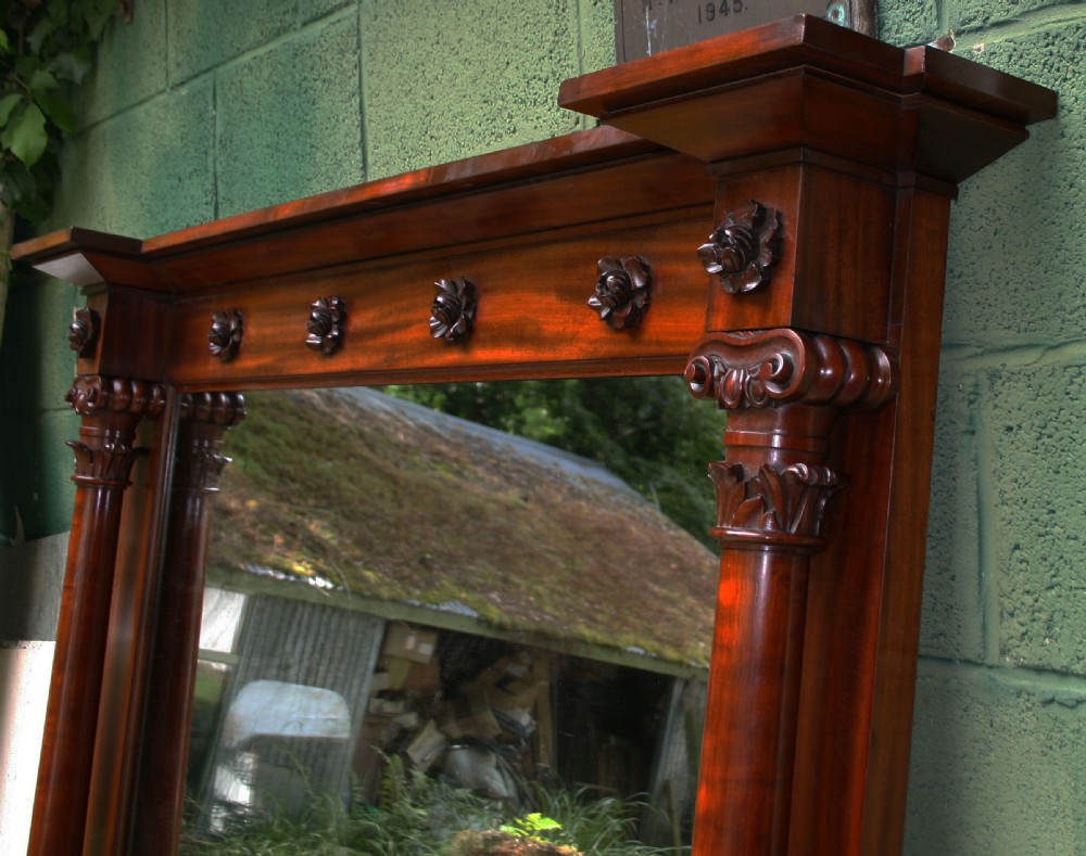 An early Victorian flame mahogany overmantel mirror featuring side columns with carved Corinthian capitals and a frieze decorated with carved rosettes. View XI