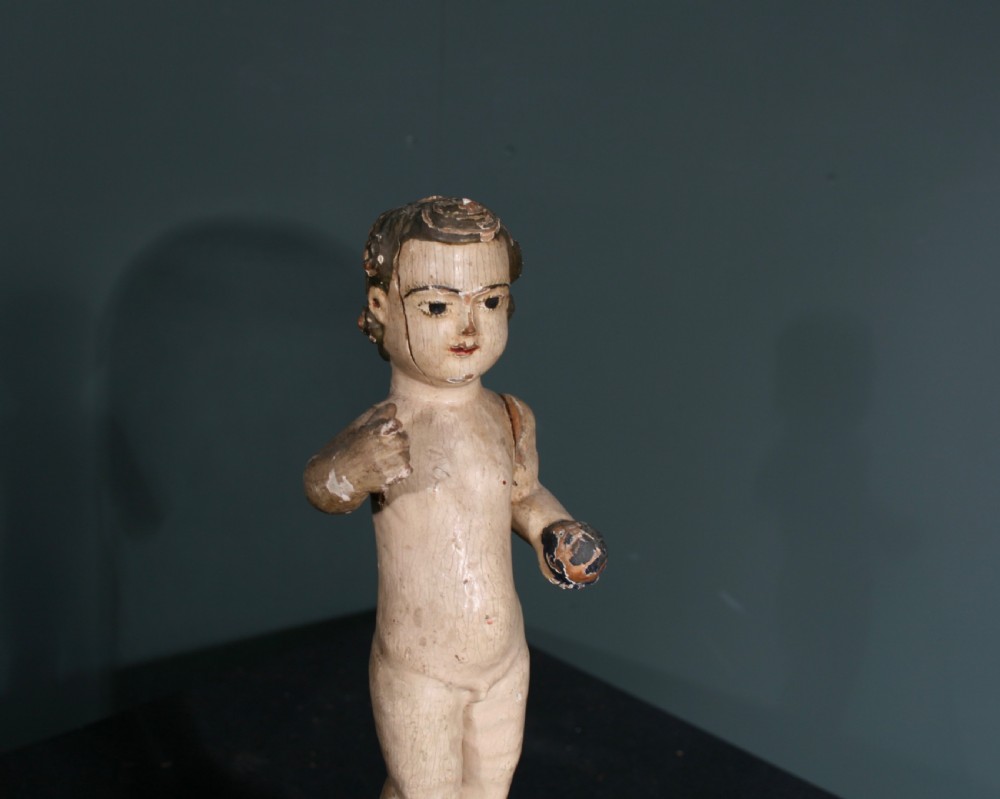 A carved wooden figure of the Christ Child holding an orb, mounted on a painted faceted base and displayed beneath a clear glass cloche. View IV