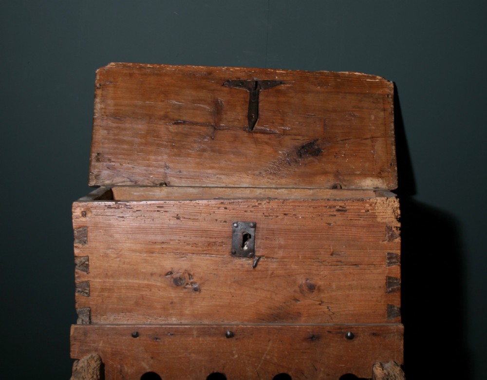 A rustic pine chest featuring exposed dovetail joints, a central iron keyhole plate, a scalloped lower apron, and carved wooden feet. View II