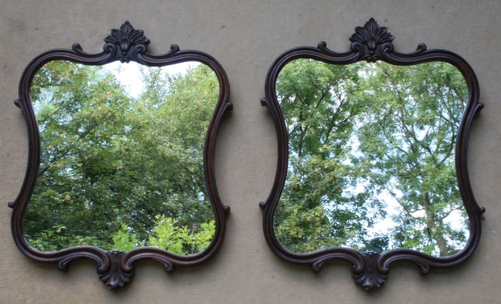 A matching pair of mid-Victorian dark rosewood wall mirrors with shaped serpentine frames and carved acanthus crests. View IV