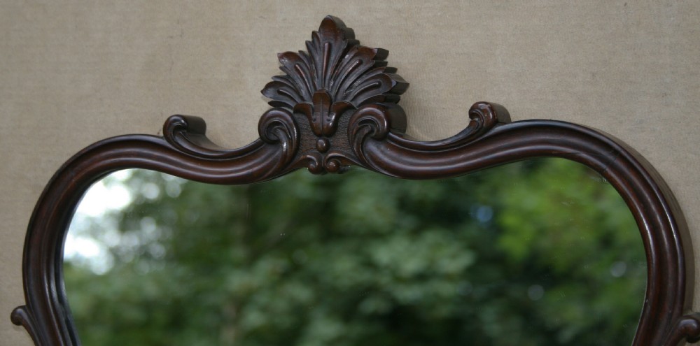 A matching pair of mid-Victorian dark rosewood wall mirrors with shaped serpentine frames and carved acanthus crests. View V