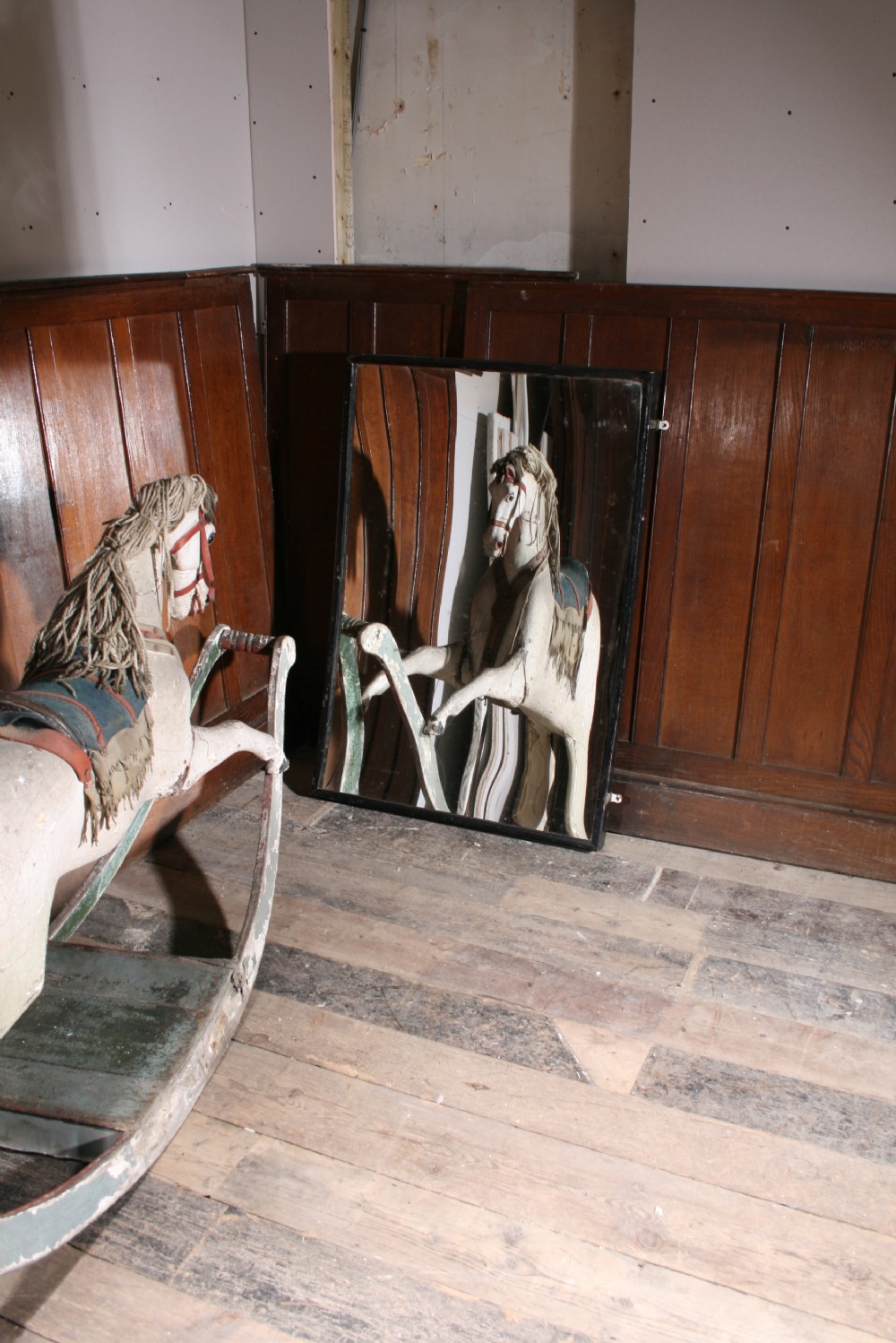 A 19th-century hand-carved wooden rocking horse in off-white painted finish mounted on green curved wooden bow rockers. View II