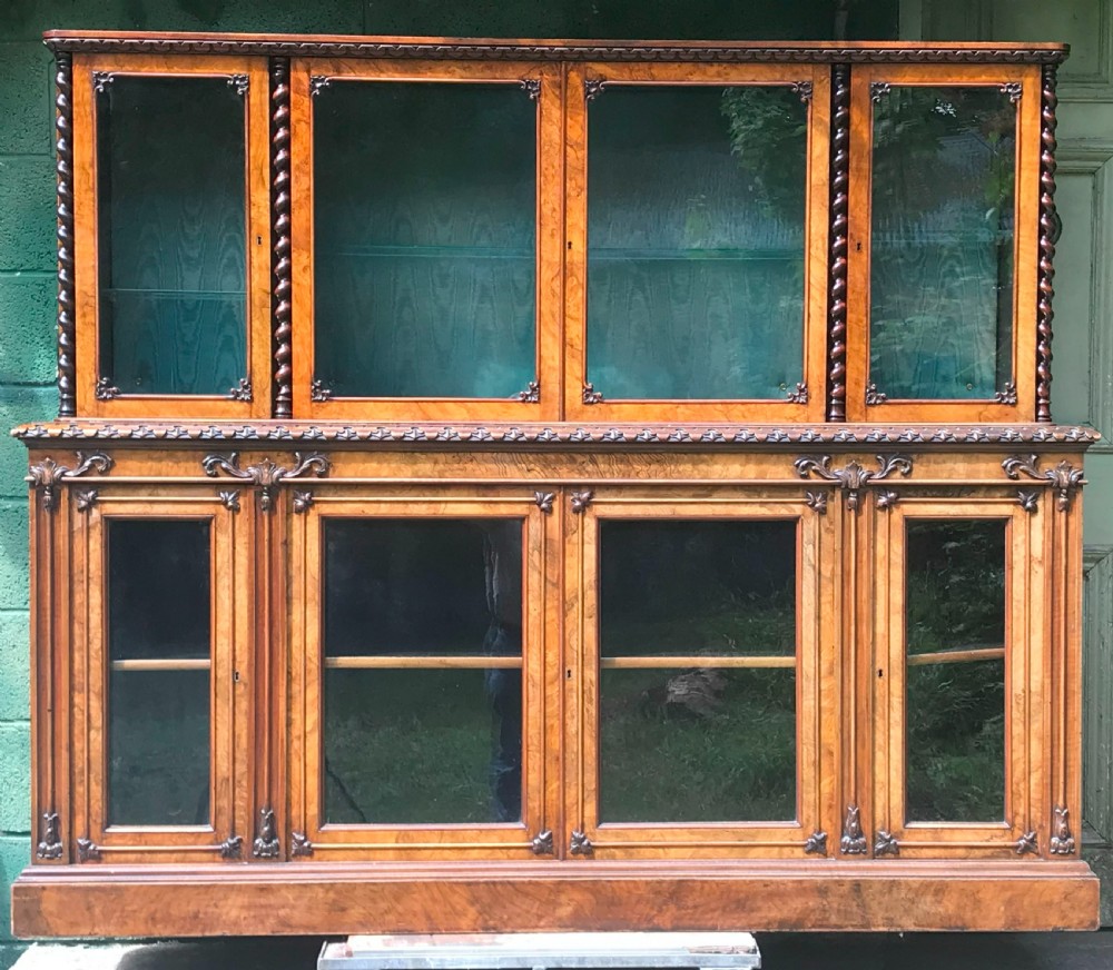 A large two-tier Victorian glazed bookcase crafted in figured walnut with spiral barley twist columns and carved mouldings.