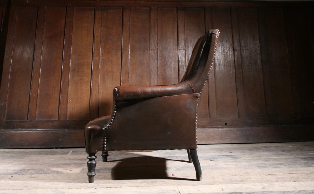 A 19th-century French armchair upholstered in dark brown patinated leather featuring brass studding trim and turned front wooden legs. View II