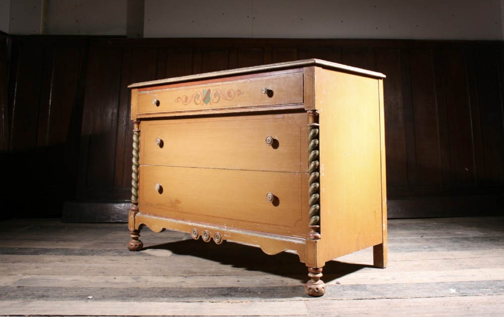 A three-drawer pine chest featuring an original yellow painted finish, rope-twist side columns, hand-painted scrollwork, and a shaped lower apron. View II