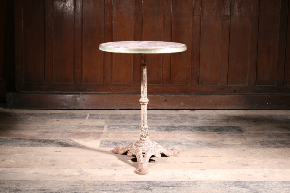 A round pink veined marble bistro table with a metal rim set upon a painted white cast iron tripod pedestal base. View III