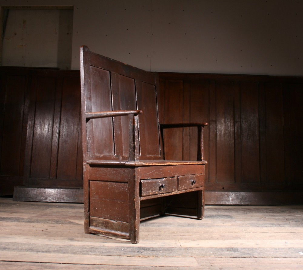 A dark brown Georgian pine settle with a high panelled back, straight wooden armrests, and two drawers set into the base. View II