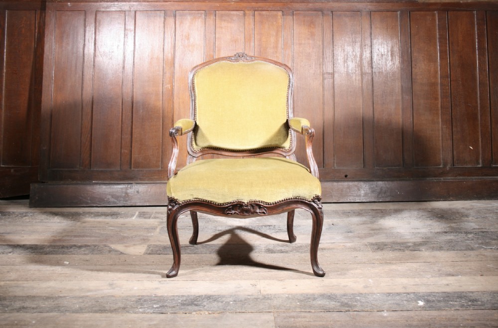 An 18th-century carved walnut armchair with olive green upholstery and cabriole legs.
