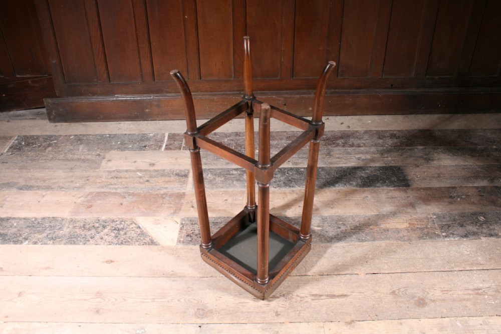 A tall antique wooden stool featuring a square padded brown leather seat with brass stud detailing and turned legs connected by stretchers. View III