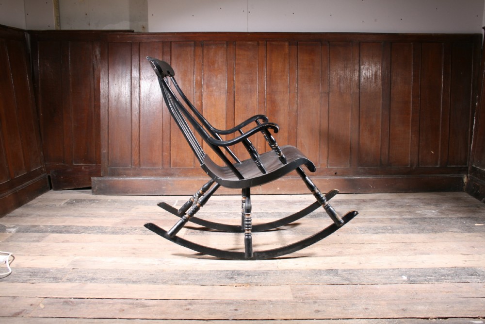 A Swedish painted wood rocking chair with a spindle back, curved armrests, turned legs, and a black distressed finish. View II