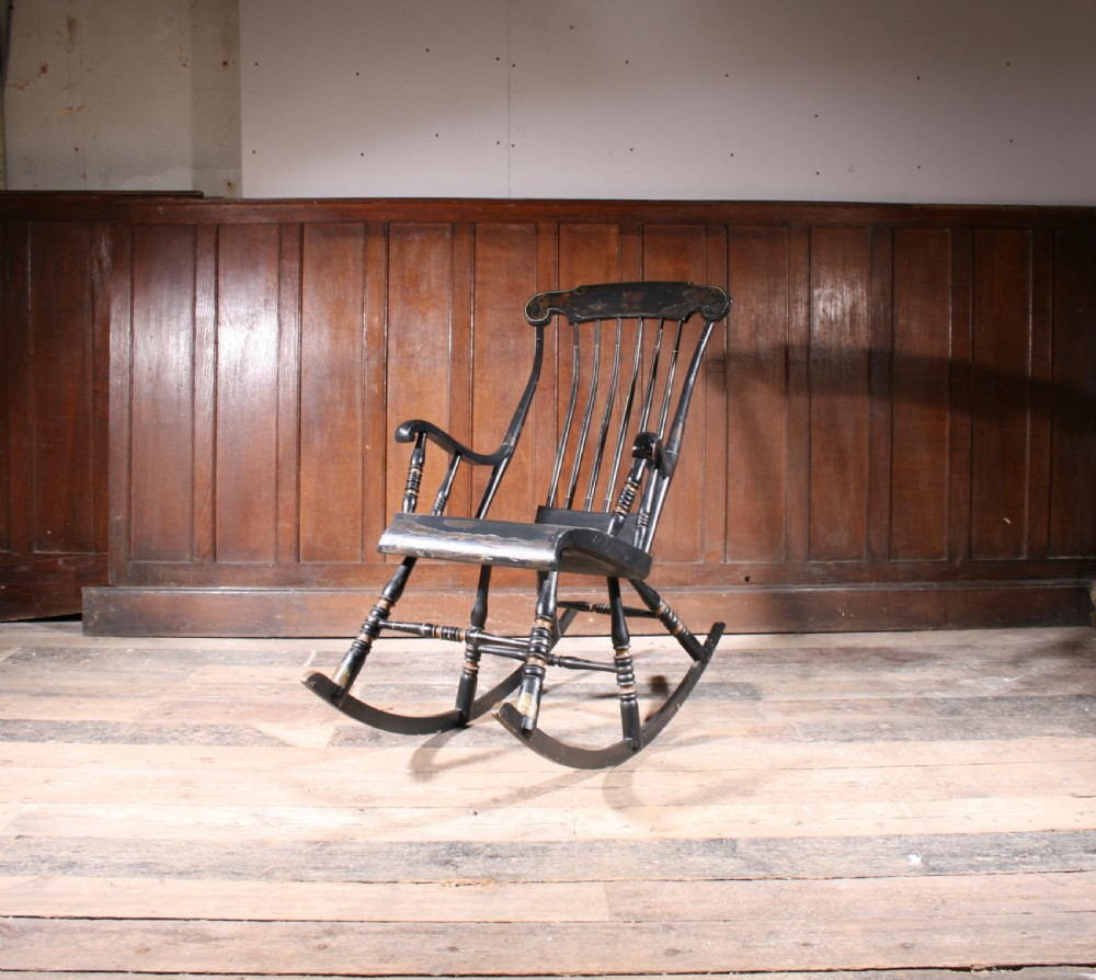 A Swedish painted wood rocking chair with a spindle back, curved armrests, turned legs, and a black distressed finish. View III