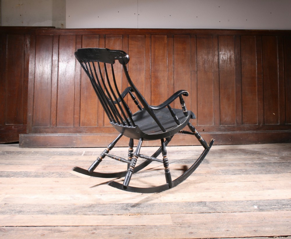 A Swedish painted wood rocking chair with a spindle back, curved armrests, turned legs, and a black distressed finish. View IV