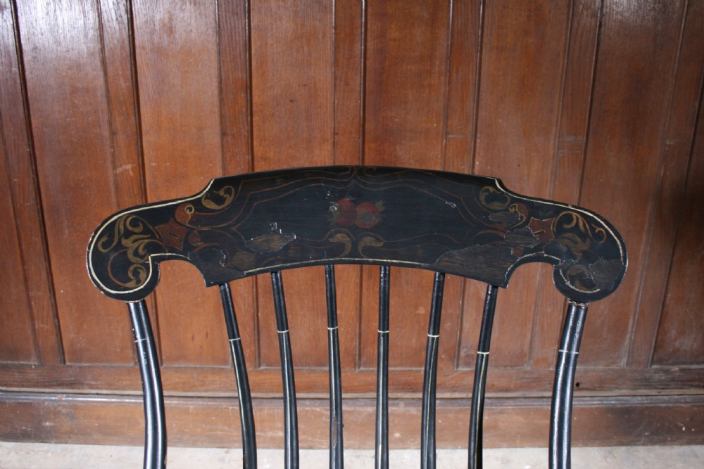 A Swedish painted wood rocking chair with a spindle back, curved armrests, turned legs, and a black distressed finish. View V