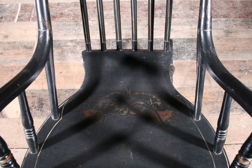 A Swedish painted wood rocking chair with a spindle back, curved armrests, turned legs, and a black distressed finish. View VI