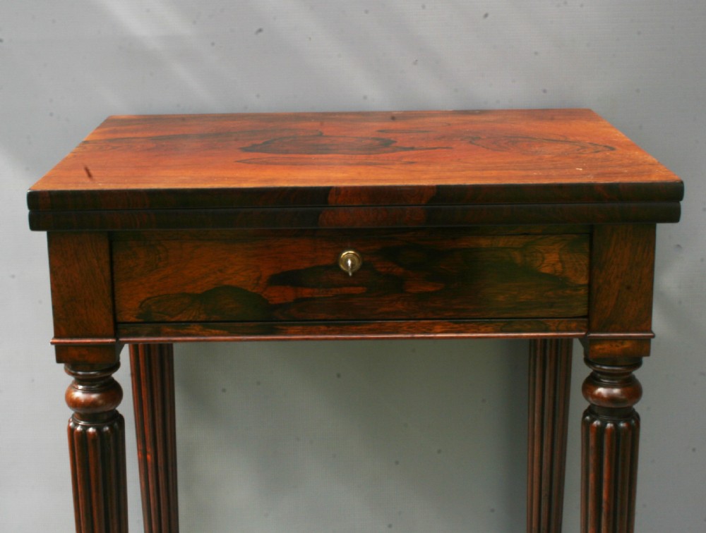 A Regency rosewood occasional table featuring a fold-over top, a single frieze drawer, and reeded turned legs with brass castors. View IV