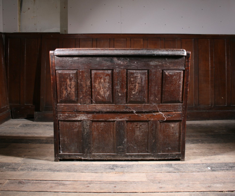 A dark brown 17th-century carved oak settle with high panelled back featuring diamond lozenge carvings and a wooden bench seat. View IX