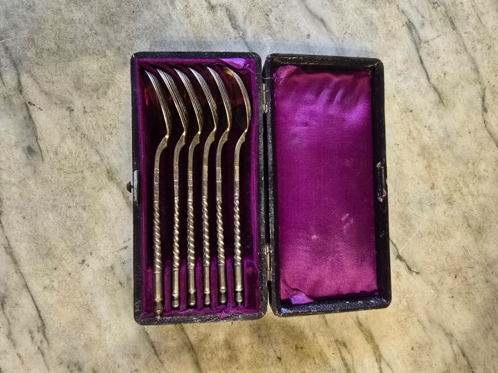 A set of six 1877 Russian niello silver spoons with twisted stems housed in a fitted black display box lined with purple velvet.