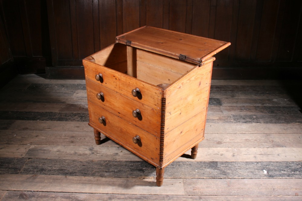 A Georgian pine mule chest featuring a hinged top lid, three lower drawer fronts with turned wooden knobs, and turned legs. View IV