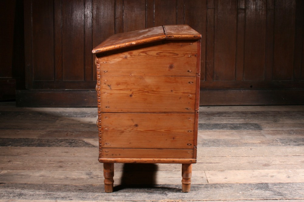 A Georgian pine mule chest featuring a hinged top lid, three lower drawer fronts with turned wooden knobs, and turned legs. View V