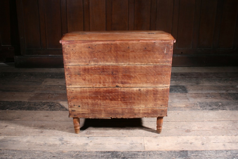 A Georgian pine mule chest featuring a hinged top lid, three lower drawer fronts with turned wooden knobs, and turned legs. View VI