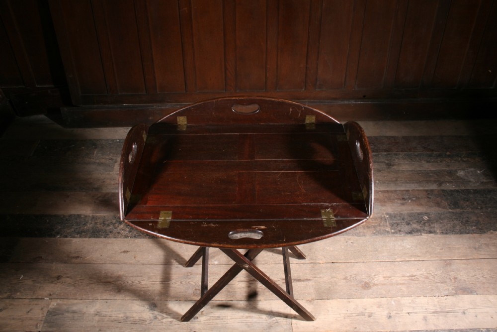 A dark mahogany Georgian butler tray with folding sides and brass hinges resting atop a matching wooden X-frame folding stand. View IV