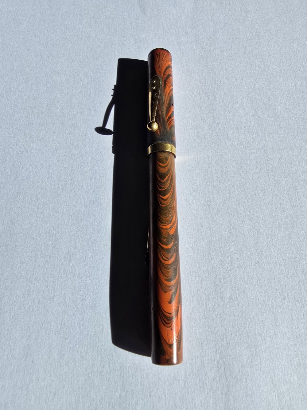 A vintage Waterman Ideal No. 7 lever-fill fountain pen crafted from red and black rippled ebonite with gold-toned trim.