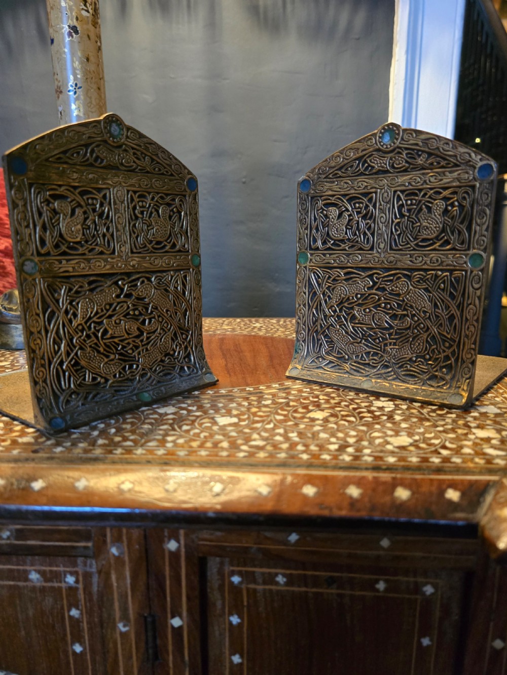 A pair of antique gilt bronze Tiffany Studios bookends featuring intricate Celtic interlace relief work and coloured cabochons.