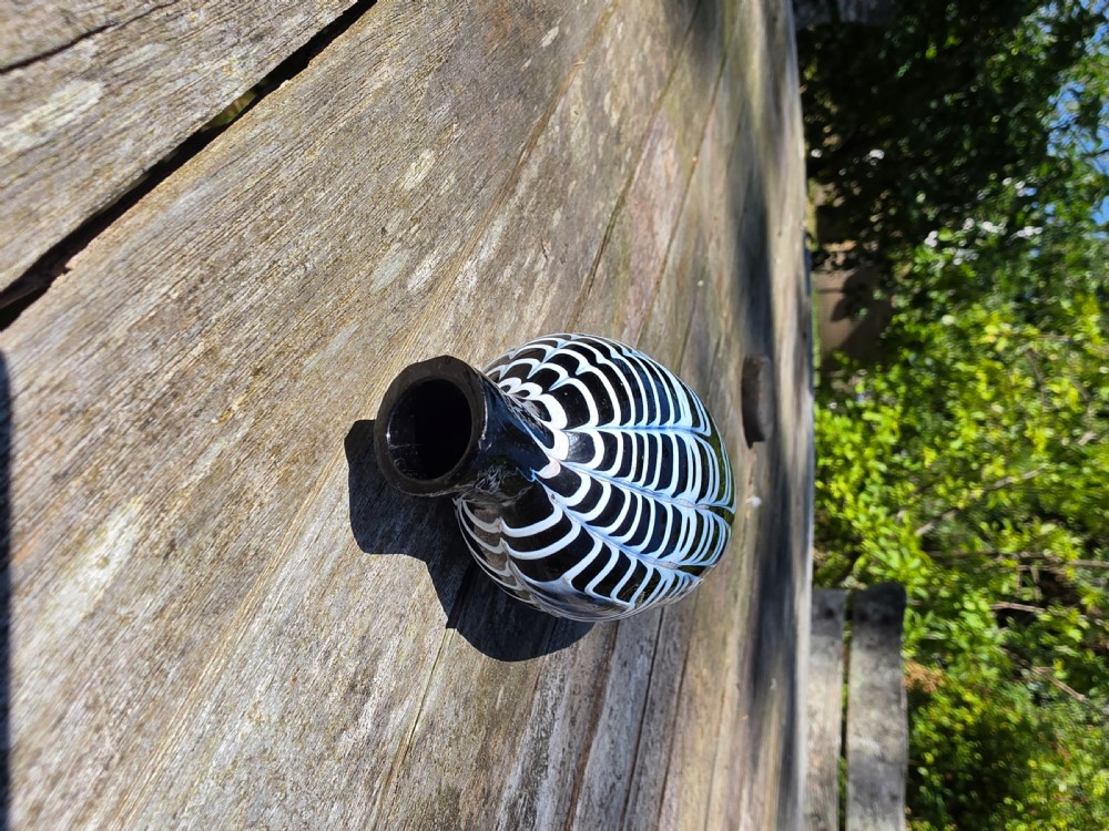 A Georgian dark glass pocket flask featuring white combed festoon trailing and a narrow neck. View VI