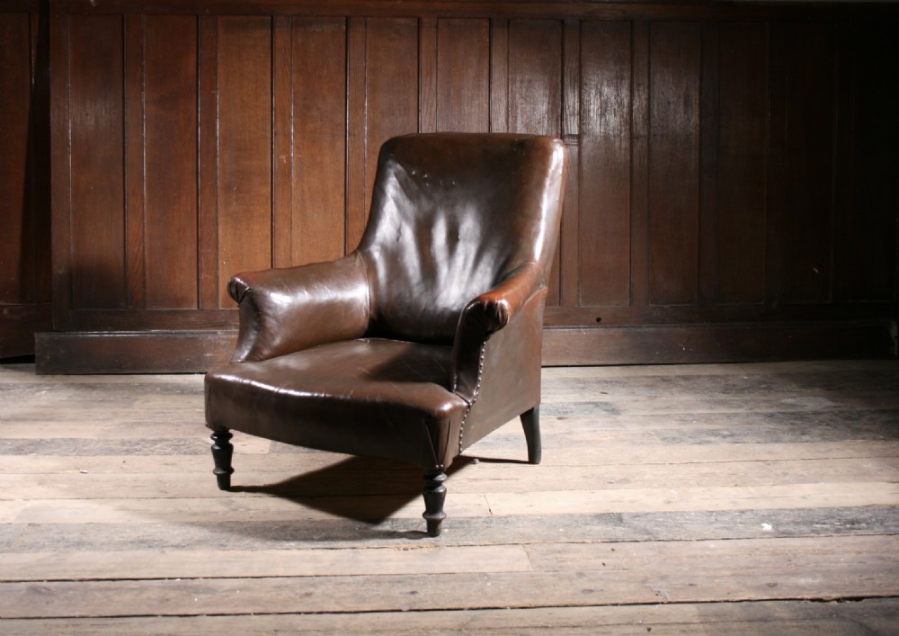 An antique nineteenth-century French armchair upholstered in dark brown leather with brass studding along the arms and dark turned wooden front legs. View II