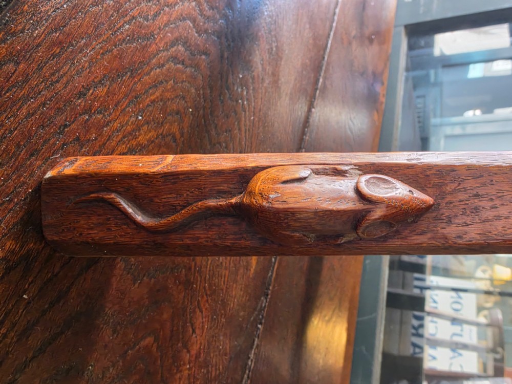 A dark English oak three-legged stool featuring an adzed kidney-shaped seat and a hand-carved mouse motif on one leg. View II