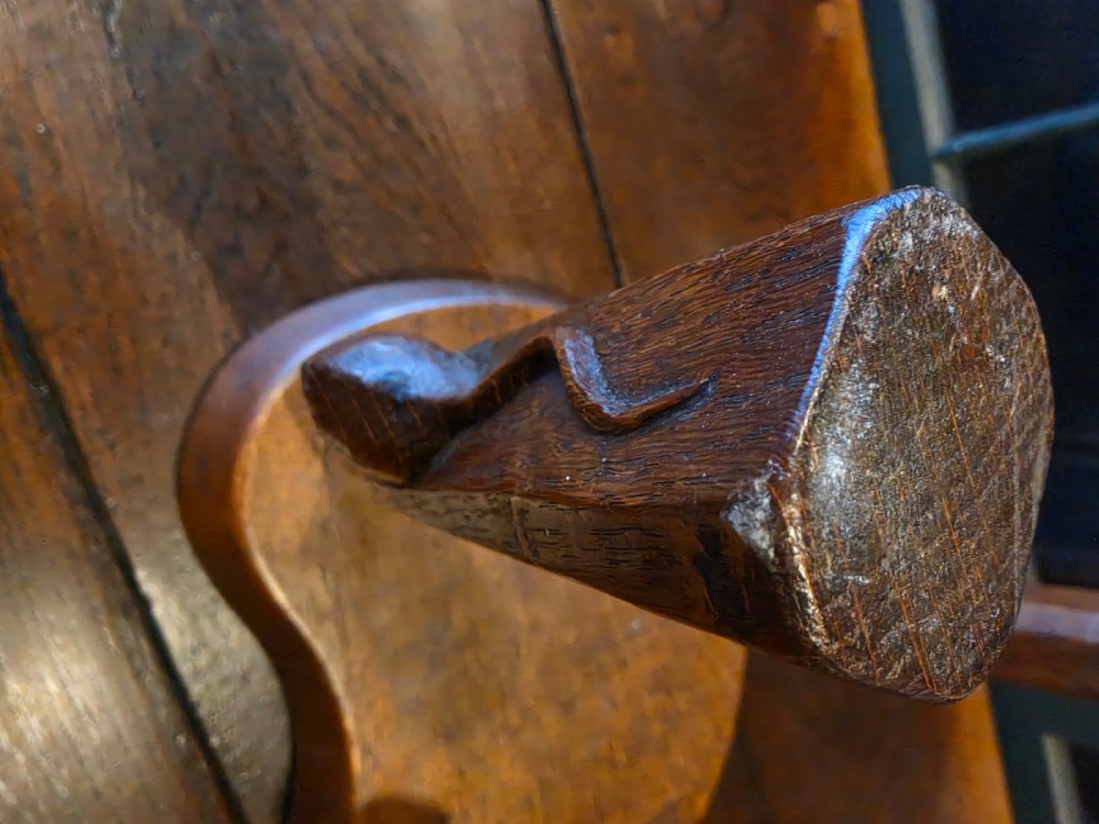 A dark English oak three-legged stool featuring an adzed kidney-shaped seat and a hand-carved mouse motif on one leg. View IV