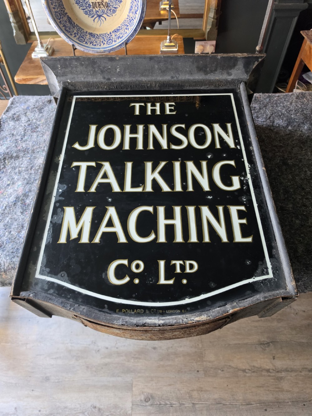 A double-sided black glass advertising lightbox with bold white lettering for The Johnson Talking Machine Co Ltd inside a metal frame.
