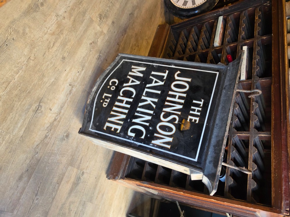 A double-sided black glass advertising lightbox with bold white lettering for The Johnson Talking Machine Co Ltd inside a metal frame. View VII