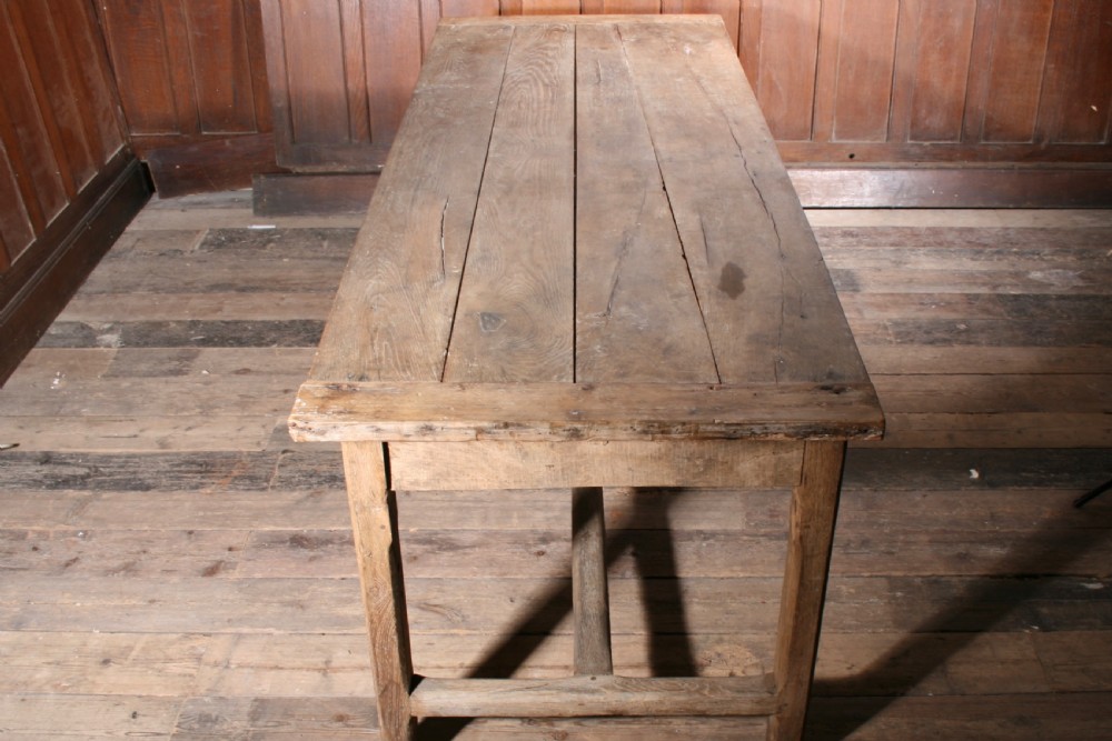 A long antique oak farmhouse dining table featuring a four-plank top, rectangular frame, square legs, and lower H-stretcher base. View II