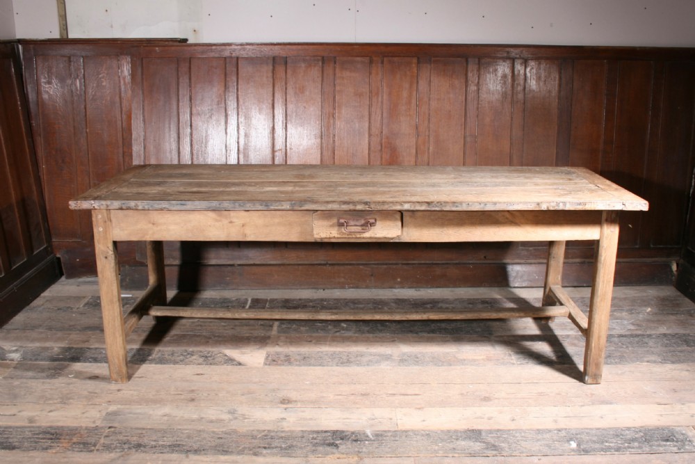 A long antique oak farmhouse dining table featuring a four-plank top, rectangular frame, square legs, and lower H-stretcher base. View VI