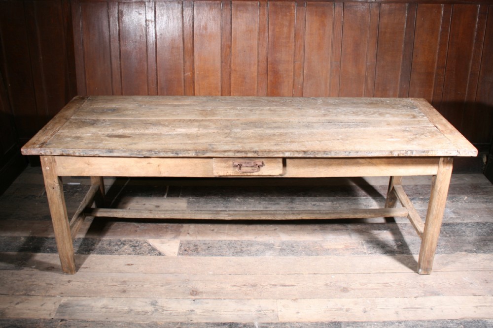 A long antique oak farmhouse dining table featuring a four-plank top, rectangular frame, square legs, and lower H-stretcher base. View VII