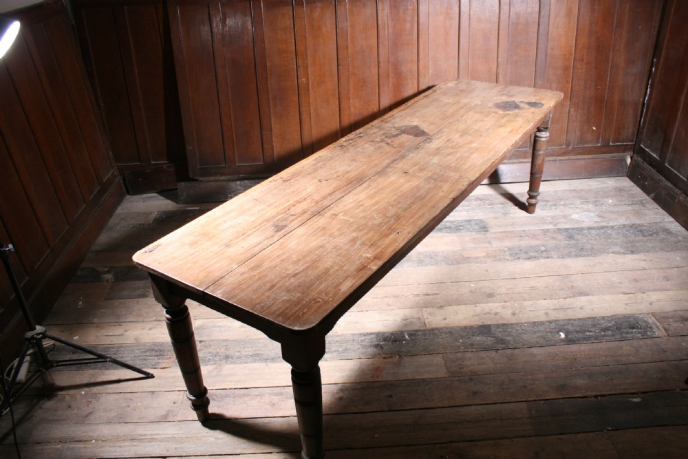 A long antique poplar farmhouse dining table featuring a twin-plank top supported by four turned wooden legs. View IV