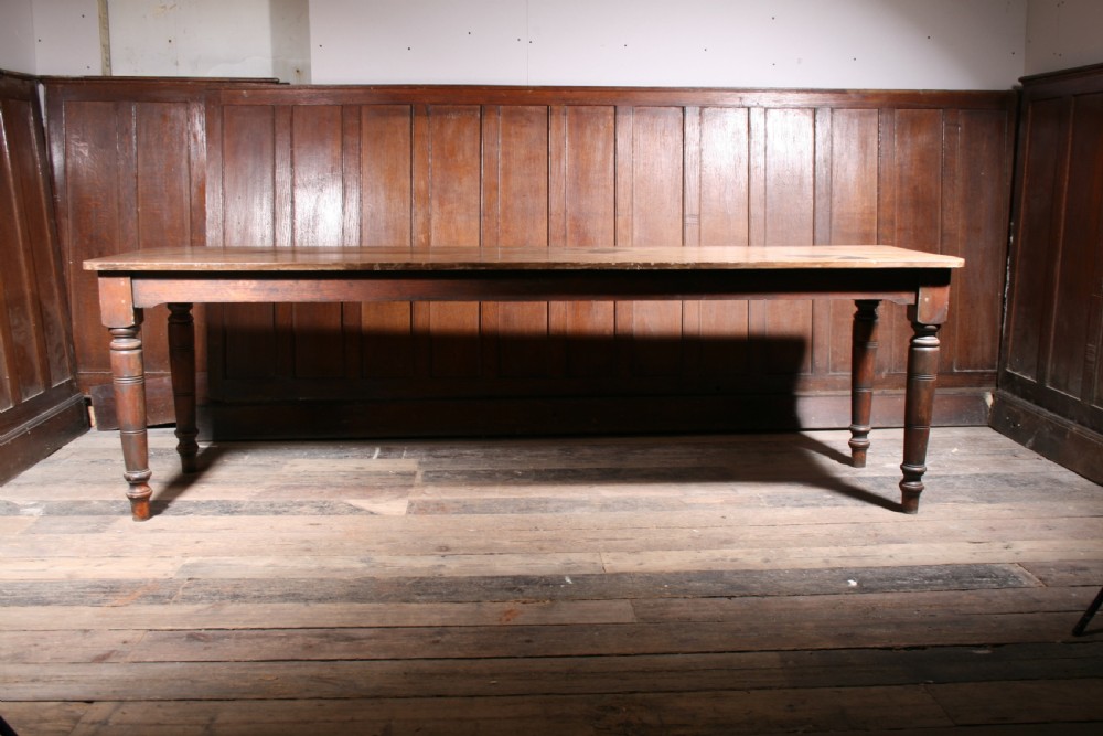 A long antique poplar farmhouse dining table featuring a twin-plank top supported by four turned wooden legs. View V