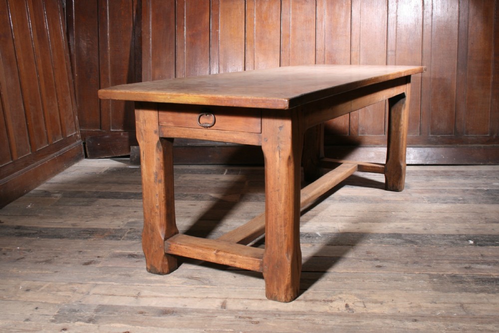 An antique walnut farmhouse dining table featuring a twin plank timber top, a single end drawer with a metal ring pull handle, and heavy legs connected by a central stretcher. View III