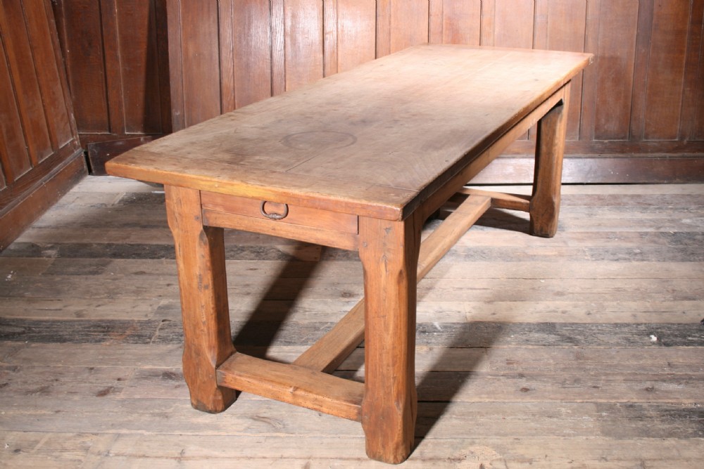 An antique walnut farmhouse dining table featuring a twin plank timber top, a single end drawer with a metal ring pull handle, and heavy legs connected by a central stretcher. View IV